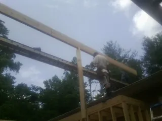 Carpenter setting a ridge beam over a new addition frame — Ice Dam Removal by Roofing Brothers in Trafford