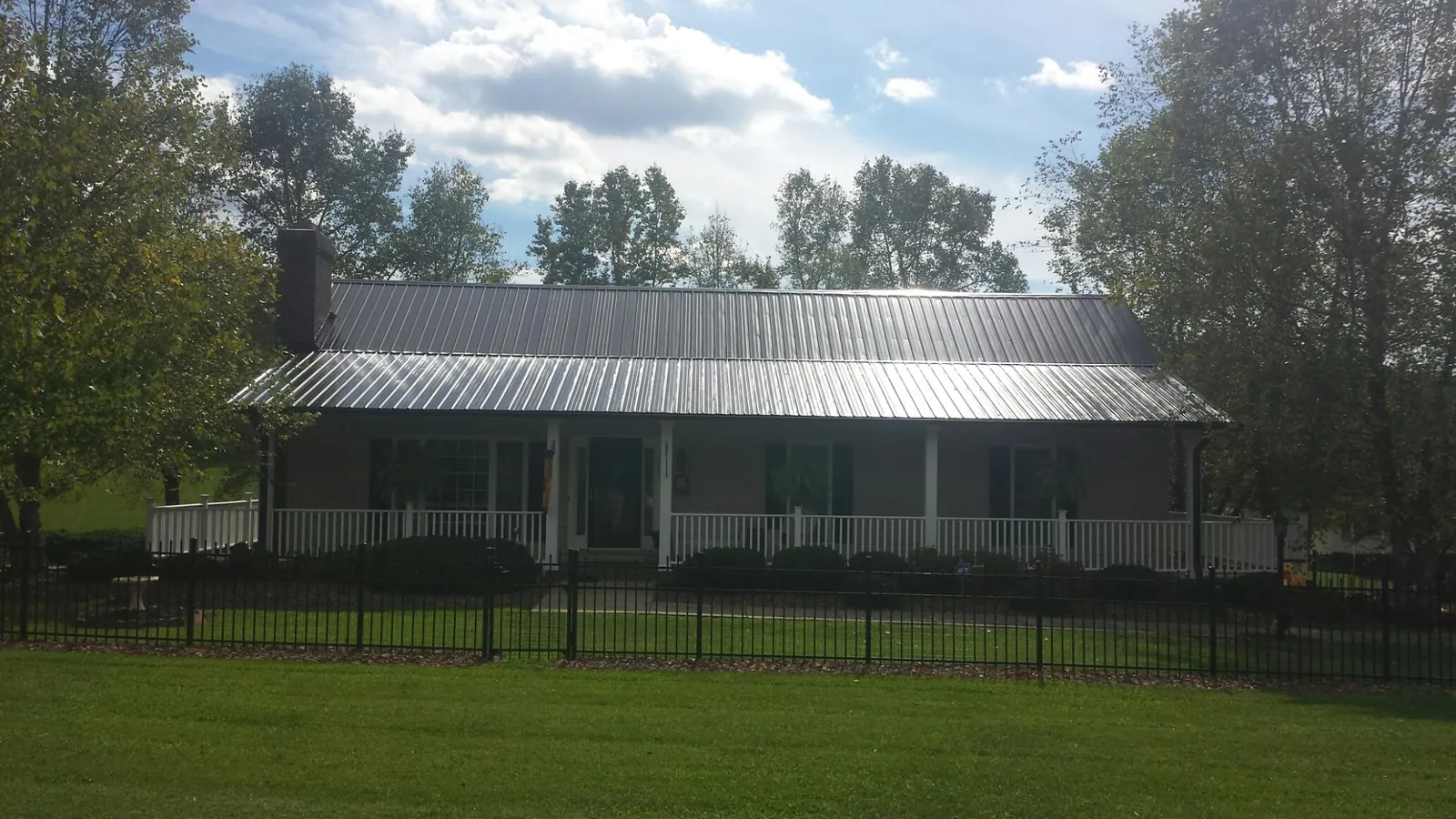 Gray metal roof on a brick ranch with a full width front porch — Gutter Guard Installation work by our crew in Trafford