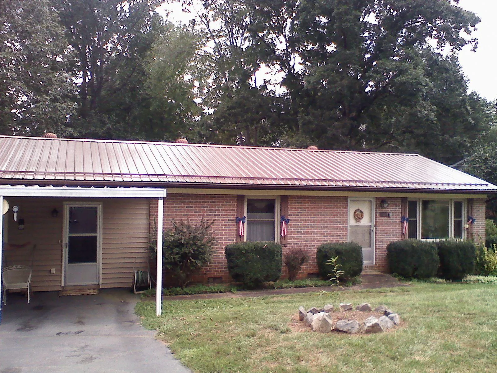 Bronze metal roof and carport on a brick ranch home — Roof Repair work by our crew in Trafford