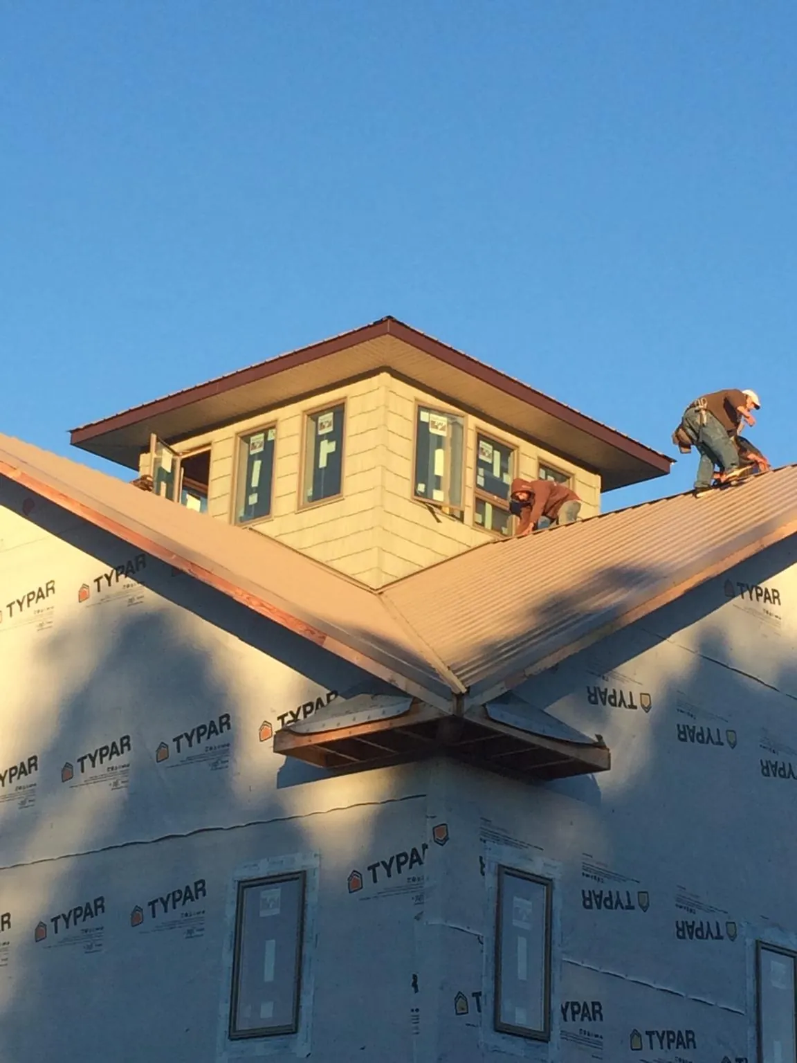Roofers working around a rooftop cupola on a new metal roof at sunset — Roof Waterproofing in Trafford by Roofing Brothers